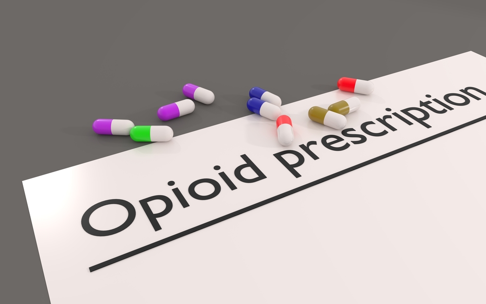 A graphic of a prescription form saying "Opioid perscription", scattered with capsules or pills.
